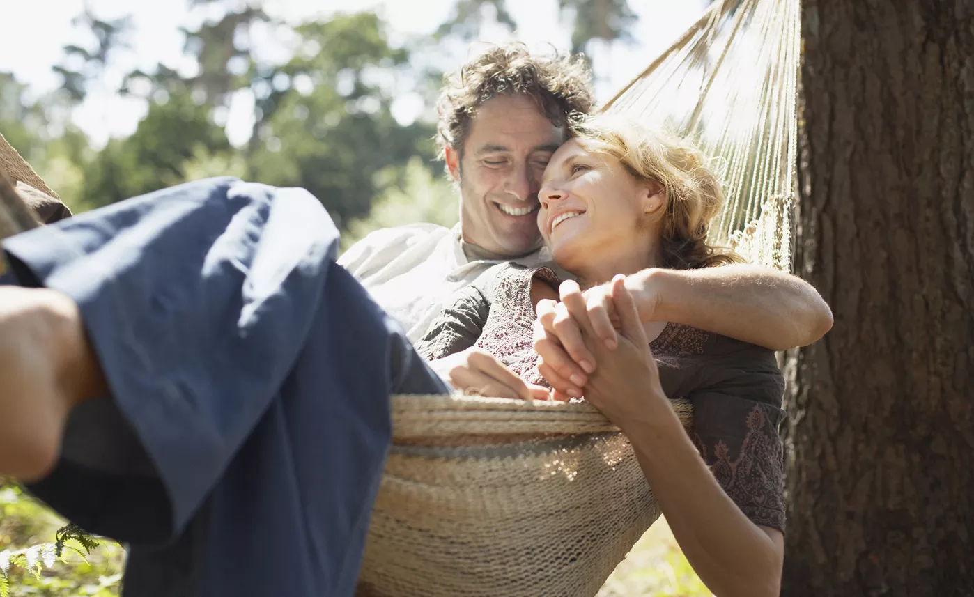  A man and woman enjoy the outdoors in a hammock.
