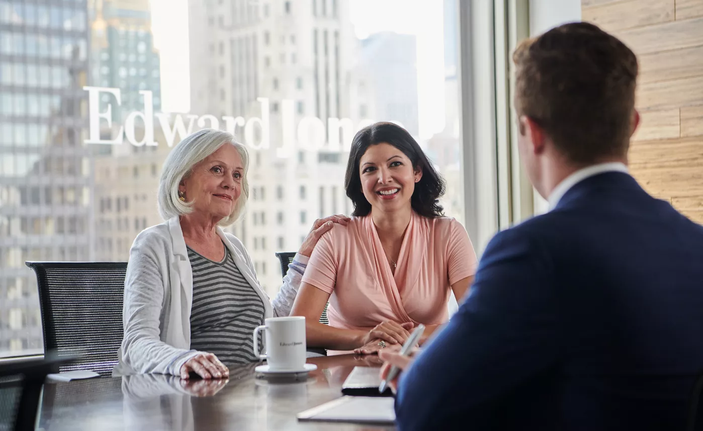  A retirement-aged woman and her daughter listen to advice from their Edward Jones financial advisor in his branch office.
