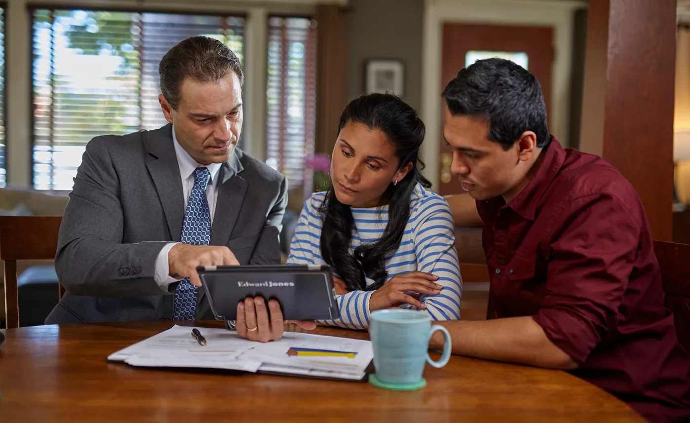  A married couple review their accounts with an Edward Jones financial advisor inside their home
