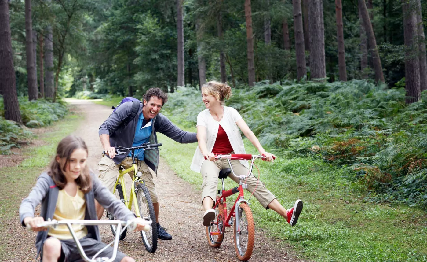 Man, woman and child riding bicycles along gravel path.
