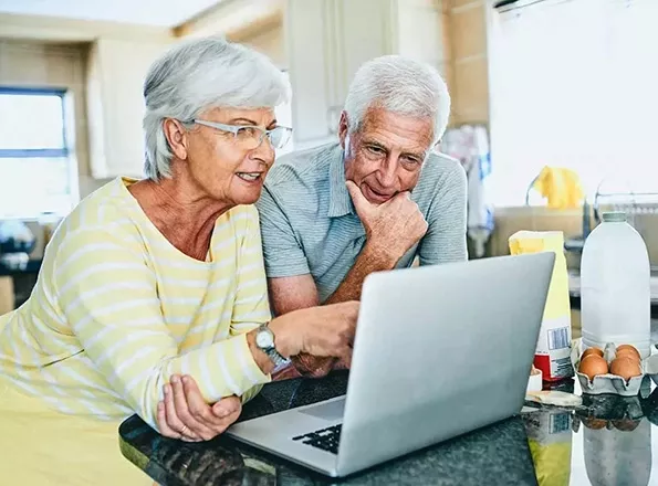  Couple in their house looking at a laptop
