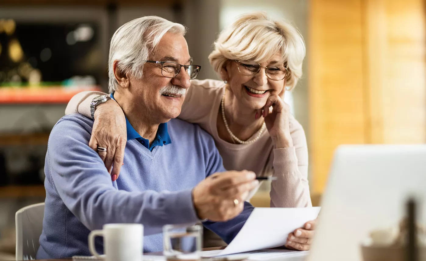  A retirement-aged couple file their taxes at home on a laptop.
