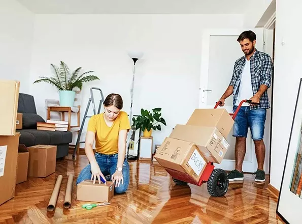  A young couple moves boxes into their new home as first-time homebuyers.
