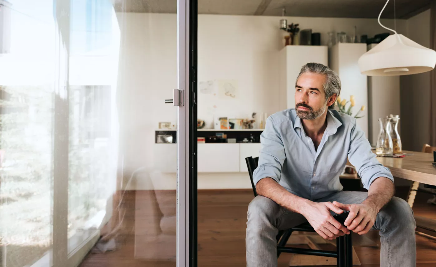  Man sitting in dining chair looking out window
