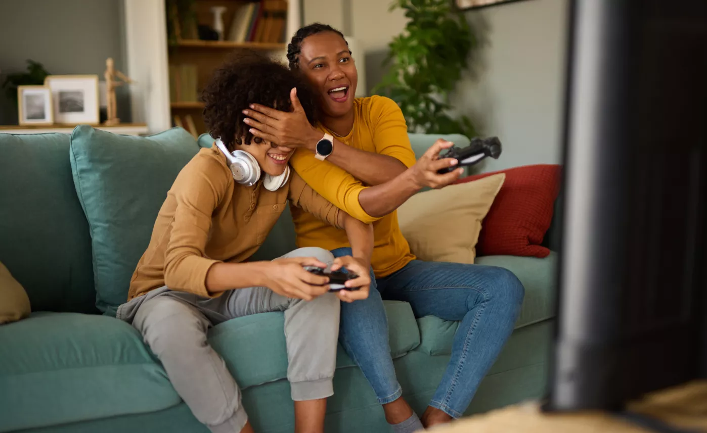  A mother and young daughter laughing while playing a video game

