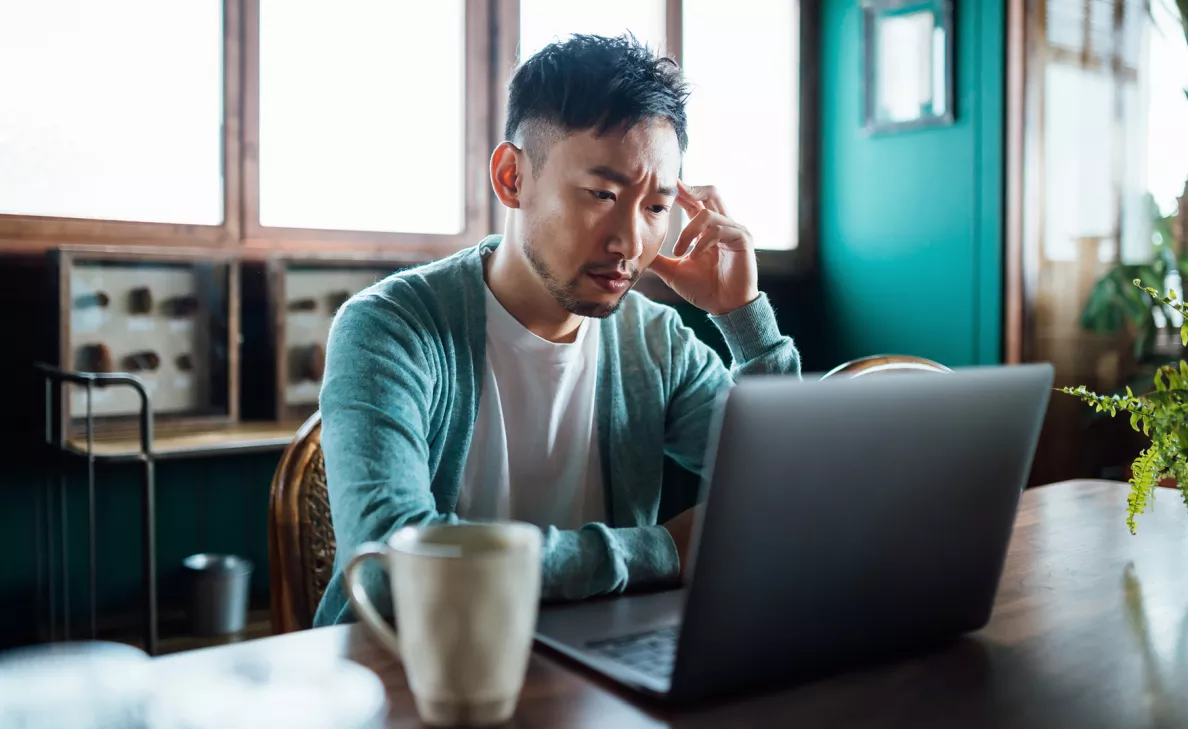  A man feeling stressed and looking at laptop

