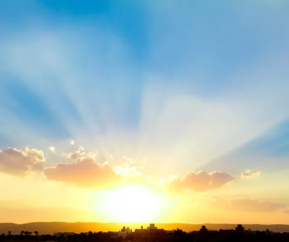  Rays of light burst through clouds during a sunset.
