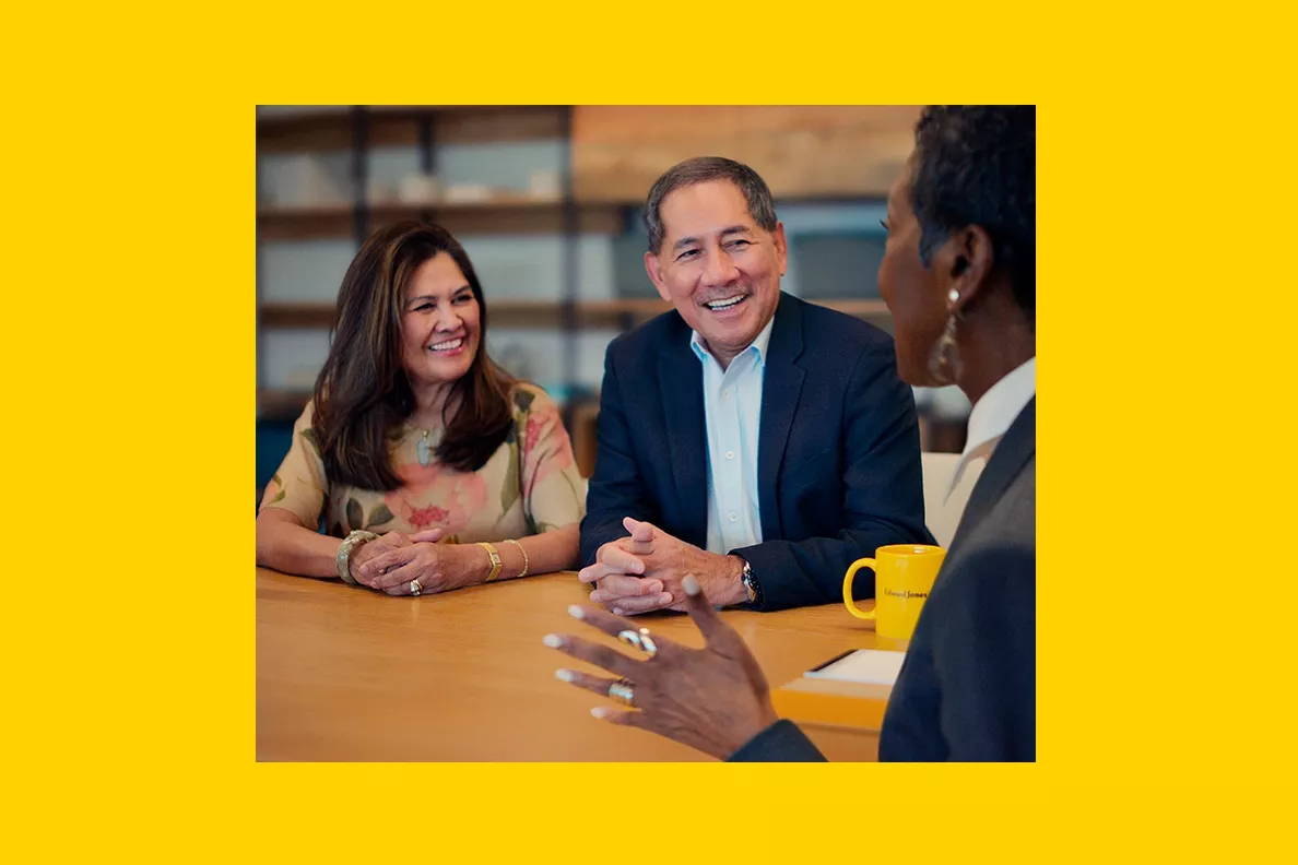  Male client and financial advisor sitting together in an office and laughing.

