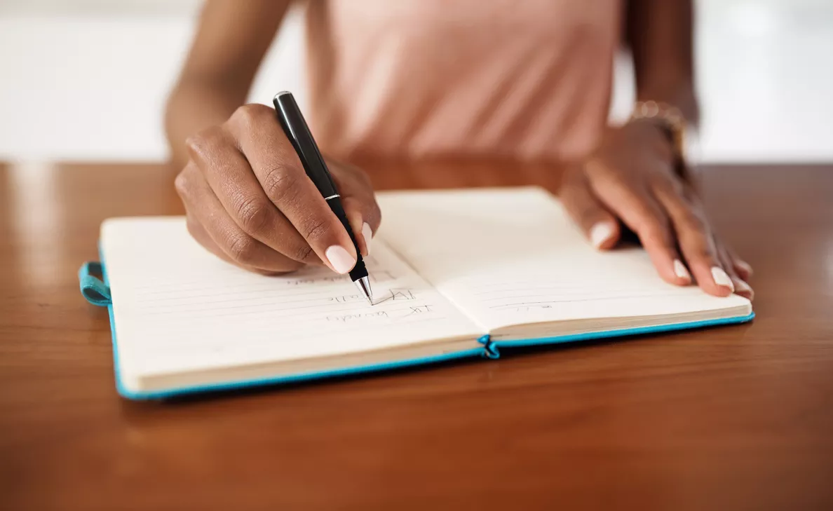 A business owner writes financial records in a notebook.