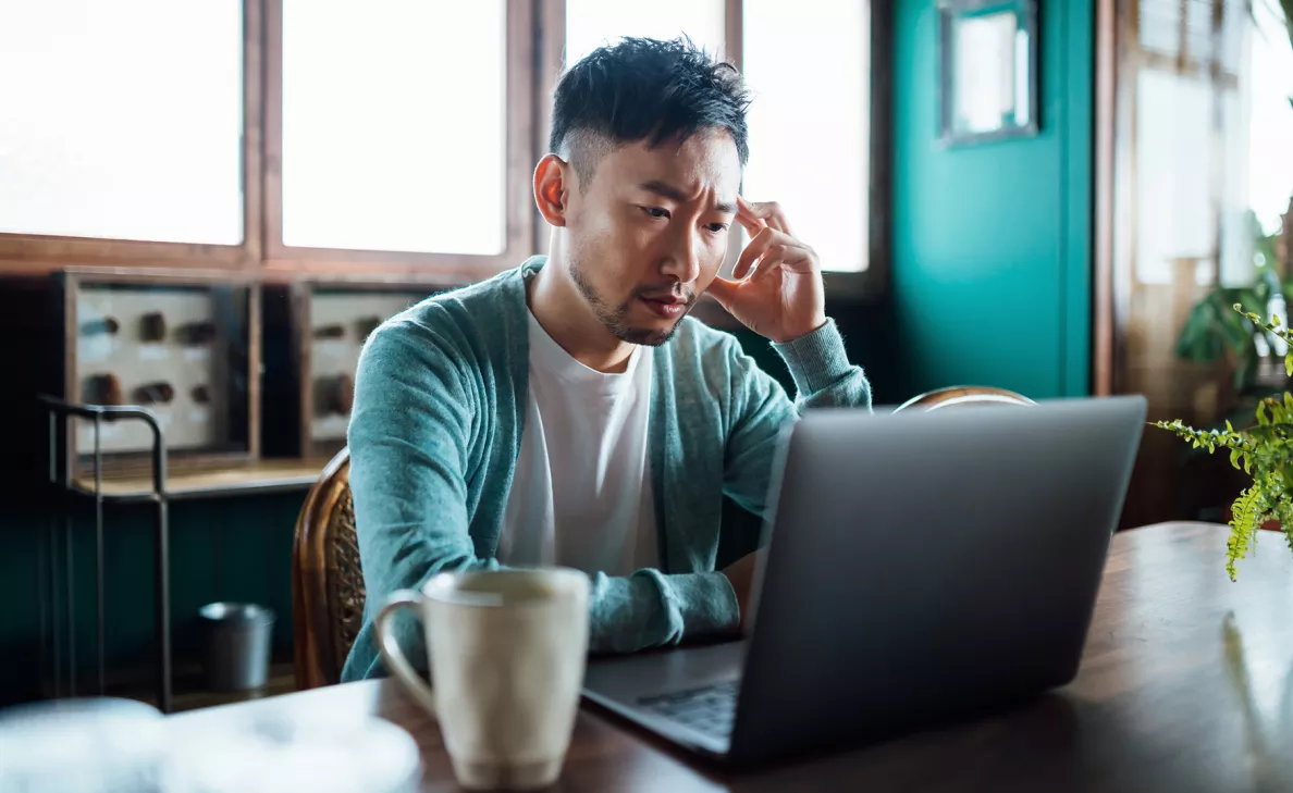A man feeling stressed and looking at laptop