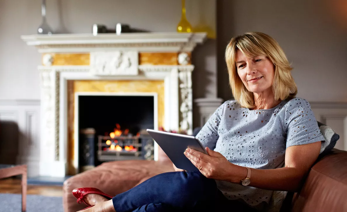 Woman sitting on sofa viewing ways to give on her tablet device