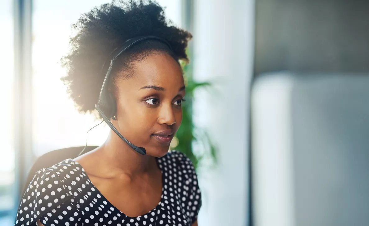 A woman with a phone headset listens to a caller.
