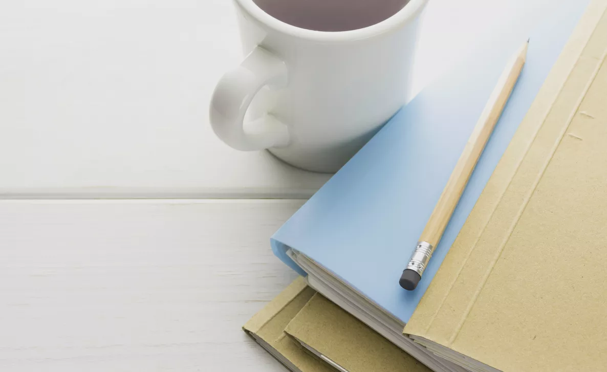  Stack of folders with a cup and pencil.
