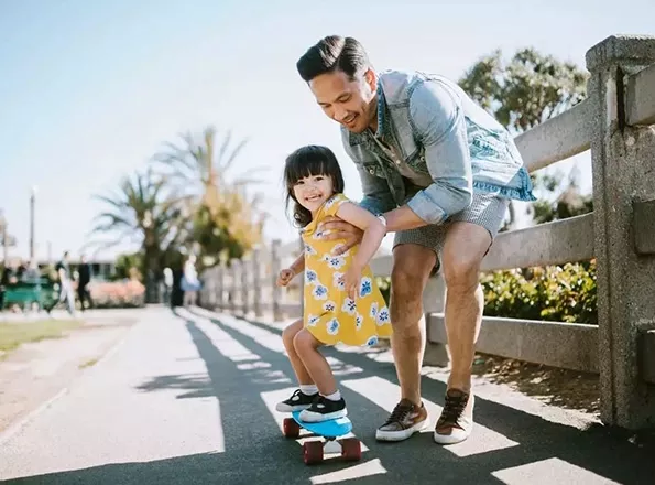  Father helping young daughter on skateboard
