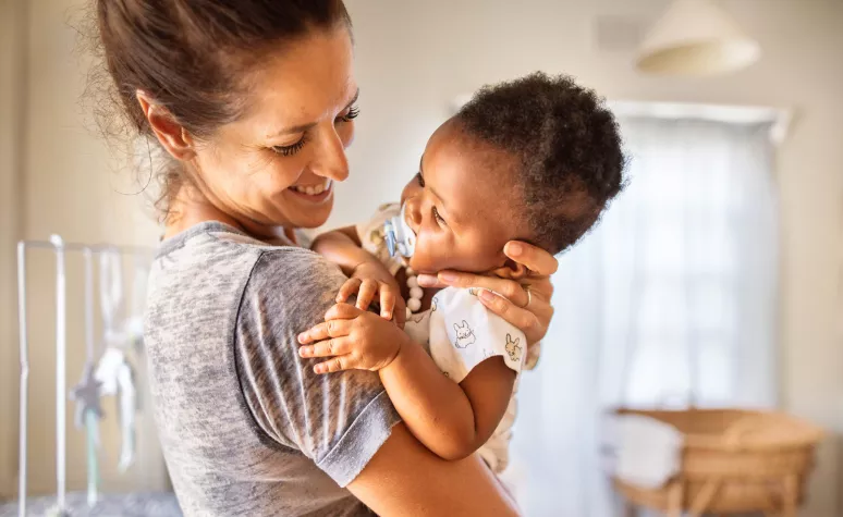 A single mom holding her young child and smiling