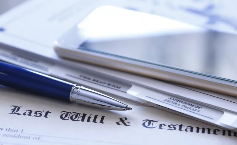 A pen and legal trust paper on top of a last will and testament. A pen and legal trust paper on top of a last will and testament.