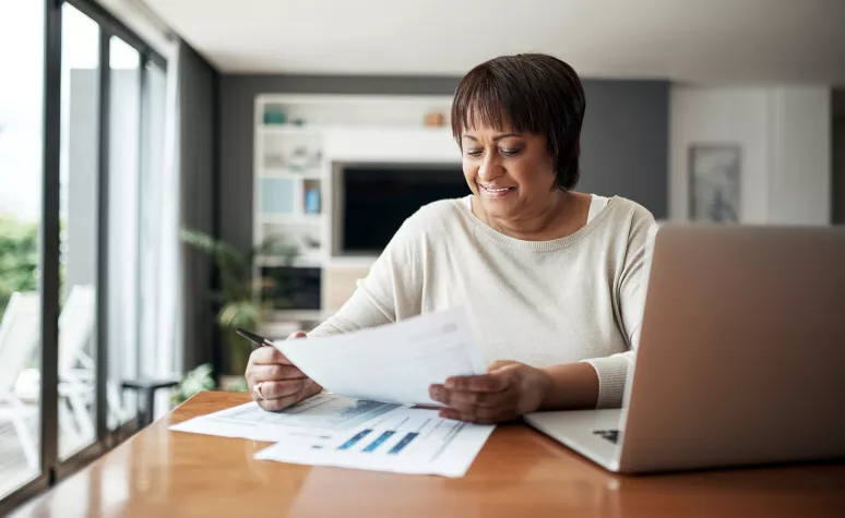Senior woman reviewing documents while using her computer