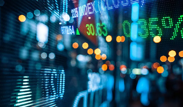 Blurred electronic stock ticker display with market numbers and lights.