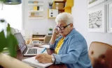 A retirement-aged woman speaks on the phone with a financial advisor as she checks her Edward Jones Income Manager account.