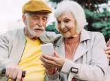 A retirement-aged couple reviews their retirement spending account on a smartphone.
