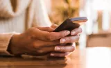 A woman reads a text message on her mobile phone.