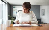 A woman fills out tax forms at a desk.