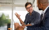 A man wearing glasses has a conversation with another man