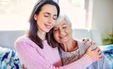 A women smiles and hugs her elderly mother.