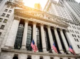 New York Stock Exchange building with American flags and surrounding skyscrapers.